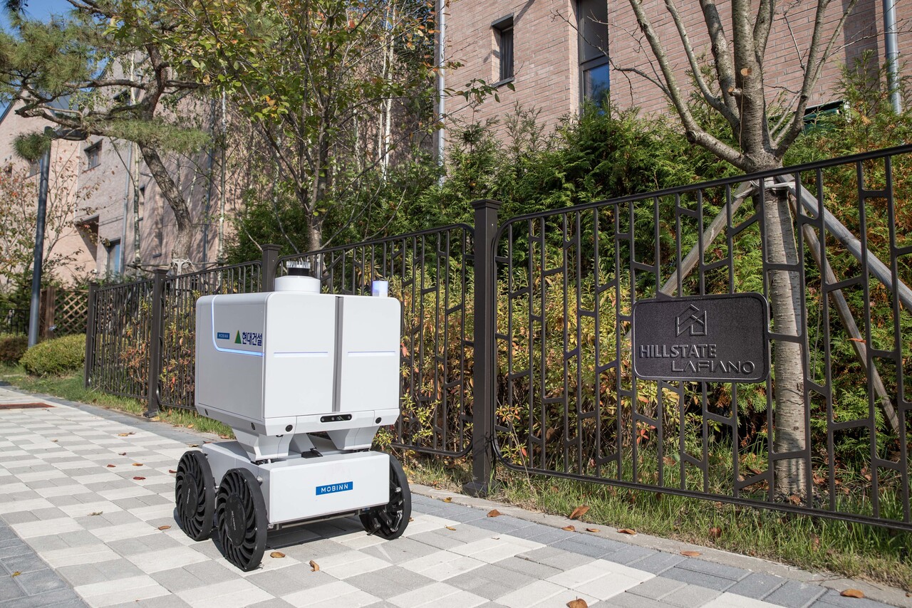 자율주행로봇이 단지 내 보행로를 이동하며 배송 서비스를 제공하고 있다. [사진=현대건설 제공]