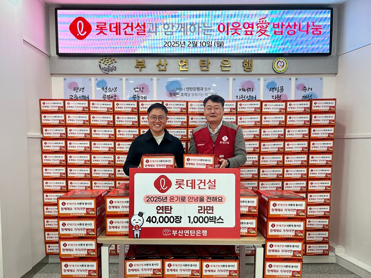 윤수준 롯데건설 영남지사장(오른쪽)과 강정칠 부산연탄은행 대표(왼쪽)가 연탄과 라면 기증판 전달식에 참여하고 있다. [사진=롯데건설 제공]