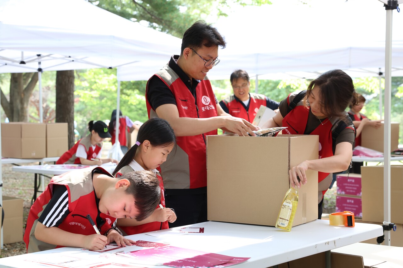 롯데건설 '샤롯데 봉사단'이 국가유공자 보훈가정을 위한 응원카드를 작성하고 기부물품을 포장하고 있다. [사진=롯데건설 제공]