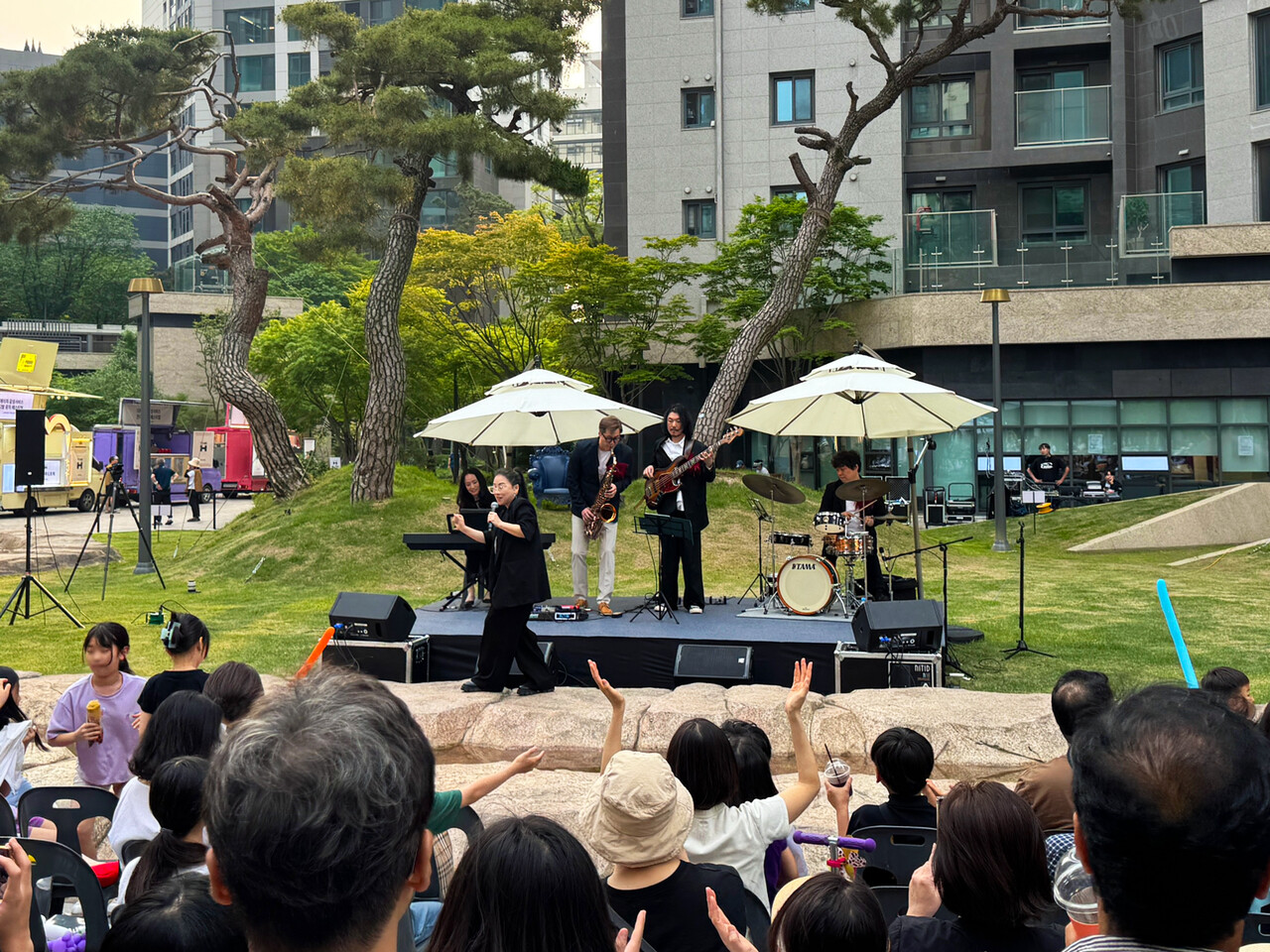 디에이치 자이 개포 단지 내 중앙광장에서 열린 ‘잔디밭 뮤직 페스티벌’에서 입주민들이 가수 난아진과 쿨재즈밴드의 공연을 즐기고 있다. [사진=현대건설 제공]
